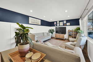 Living area featuring a wainscoted wall, a decorative wall, wood finished floors, and recessed lighting