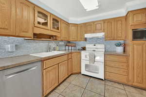 Kitchen featuring range with two ovens, stainless steel dishwasher, light countertops, under cabinet range hood, and a sink