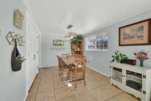 Dining room with ornamental molding, light tile patterned flooring, and baseboards