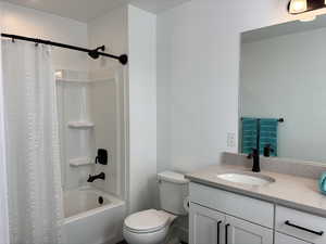 Full bathroom featuring toilet, shower / bath combo, and vanity