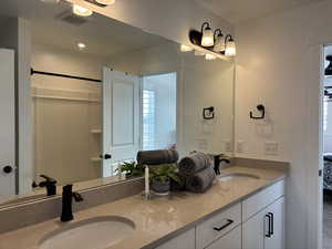 Ensuite bathroom featuring ensuite bathroom, double vanity, a sink, and visible vents