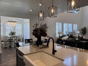 Kitchen with dark wood finished floors, hanging light fixtures, an inviting chandelier, a textured ceiling, and a sink