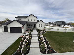 Modern farmhouse style home with driveway, fence, a garage, board and batten siding, and a front yard