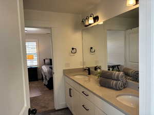 Ensuite bathroom with double vanity, a sink, and connected bathroom