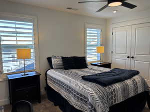Carpeted bedroom featuring ceiling fan, a closet, visible vents, and baseboards