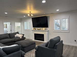 Living area featuring baseboards, a glass covered fireplace, wood finished floors, and recessed lighting
