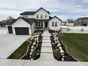 Modern inspired farmhouse featuring board and batten siding, a front lawn, fence, and a garage