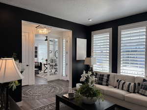 Living area featuring plenty of natural light, french doors, a textured ceiling, and wood finished floors