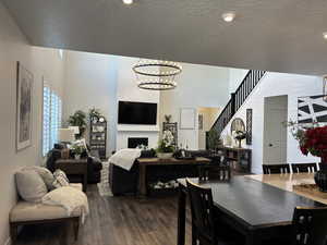 Dining space featuring a chandelier, a textured ceiling, a fireplace, wood finished floors, and stairway