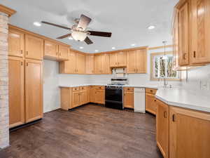 Kitchen with pendant lighting, dark wood finished floors, light countertops, a sink, and gas range