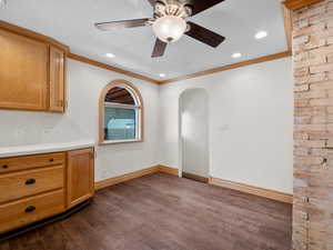 Interior space with crown molding, light countertops, dark wood finished floors, and baseboards