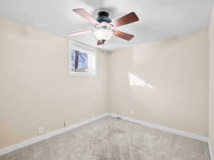 Unfurnished room featuring light carpet, a ceiling fan, and baseboards