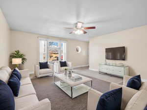 Carpeted living room with ceiling fan and baseboards