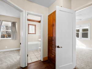 Hall with baseboards and dark colored carpet