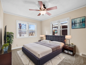 Bedroom with multiple windows, visible vents, crown molding, and light colored carpet