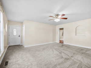 Interior space featuring carpet floors, visible vents, baseboards, and a ceiling fan