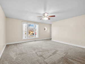 Unfurnished room with carpet floors, ceiling fan, and baseboards