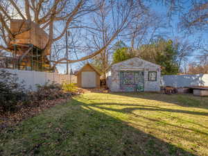 View of yard featuring a shed, a fenced backyard, and an outbuilding