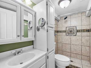 Full bath featuring toilet, a shower stall, a textured ceiling, and vanity