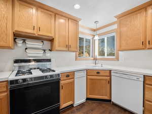 Kitchen featuring white dishwasher, light countertops, pendant lighting, a sink, and gas stove