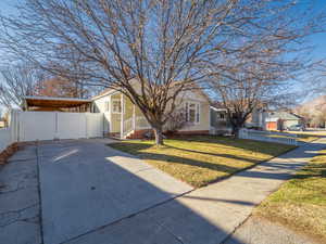 View of front of property featuring a front yard, concrete driveway, fence, and a residential view