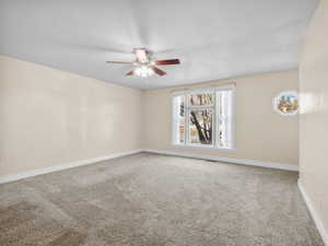 Spare room featuring carpet floors, visible vents, ceiling fan, and baseboards