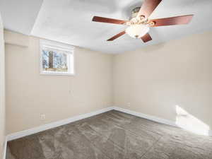 Spare room featuring carpet, baseboards, and a textured ceiling