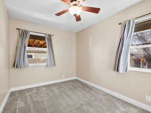 Empty room featuring a ceiling fan, light carpet, and baseboards