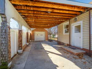 View of patio / terrace featuring a garage, an outdoor structure, a carport, and fence