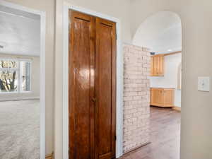 Hallway featuring baseboards, arched walkways, wood finished floors, and carpet flooring