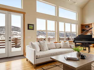 Living area with a towering ceiling, light wood-style floors, a mountain view, and track lighting