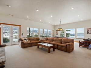 Living room featuring french doors, visible vents, light carpet, and a textured ceiling