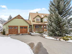 View of front of property with aphalt driveway, an attached garage, stone siding, stucco siding, and a chimney