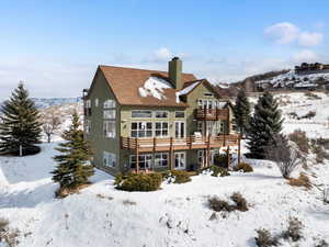 Snow covered house featuring a chimney and a balcony