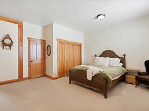 Bedroom featuring a closet, light colored carpet, and baseboards