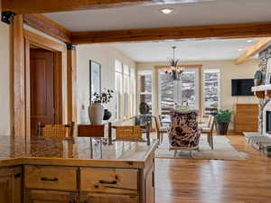 Kitchen featuring beam ceiling, a fireplace, tile countertops, hanging light fixtures, and brown cabinetry