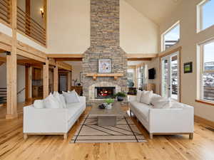 Living room featuring a towering ceiling, light wood-style floors, a fireplace, and baseboards