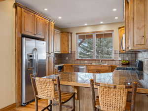 Kitchen with tile countertops, a peninsula, a breakfast bar, a sink, and appliances with stainless steel finishes