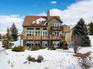 Snow covered property with french doors, a chimney, and a wooden deck