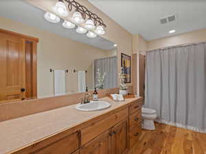 Full bathroom featuring toilet, vanity, wood finished floors, and visible vents