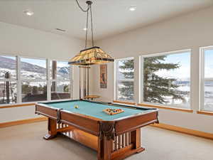 Rec room featuring light carpet, plenty of natural light, a mountain view, and baseboards