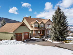 View of front of house with an attached garage, a mountain view, aphalt driveway, and stucco siding