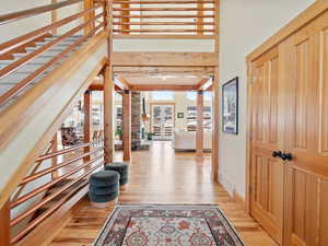 Entryway with light wood finished floors, baseboards, a high ceiling, beamed ceiling, and ornate columns