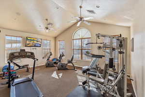 Exercise area with a ceiling fan, lofted ceiling, visible vents, and a textured ceiling