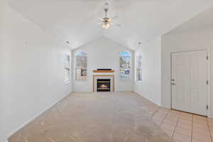 Living room with light carpet, ceiling fan, vaulted ceiling, a textured ceiling, and a fireplace