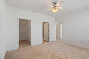 Main bedroom with a spacious closet, baseboards, a closet, and light colored carpet