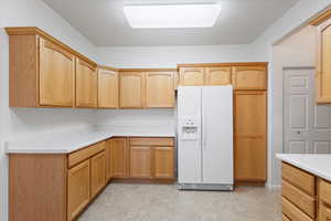 Kitchen with white fridge with ice dispenser and light countertops