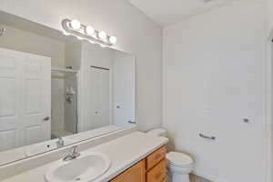 Bathroom in main bedroom featuring vanity, a closet, a shower stall with bench and toilet