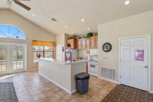 Kitchen featuring light countertops, white appliances, visible vents, and a kitchen island