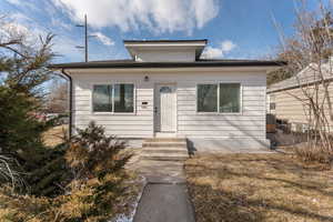 Bungalow featuring entry steps and fence